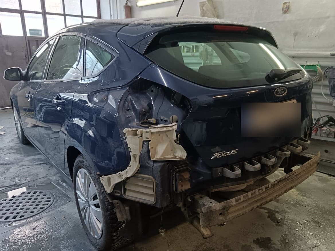 Ford Focus albastru cu spatele distrus, aripa și bara desfăcute, înainte de reparație