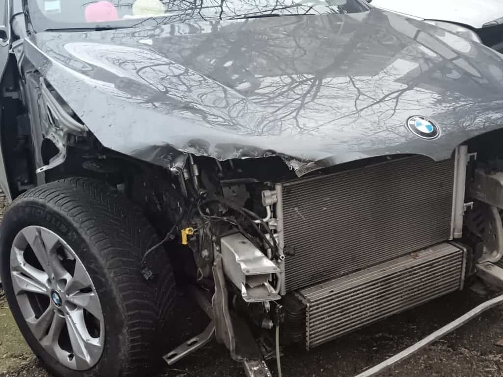BMW X1 gri cu partea din față distrusă și radiatoarele la vedere, înainte de reparație