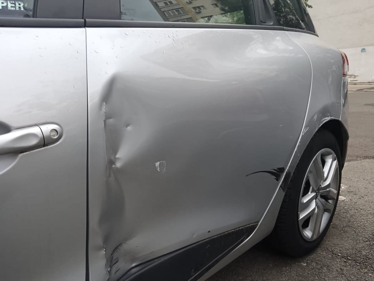 Renault Clio argintiu cu ușa din spate înfundată, înainte de reparație