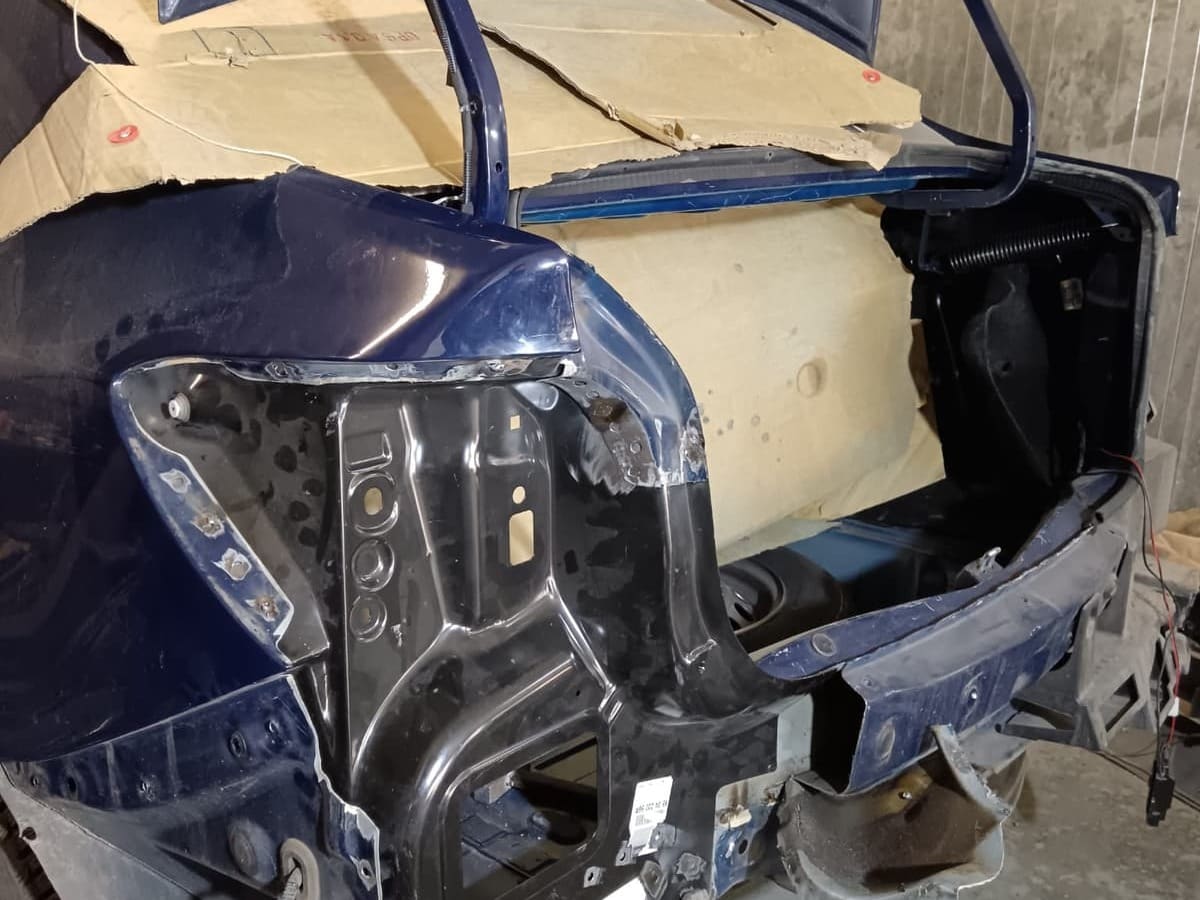 Dacia Logan albastră cu aripa din spate și bara desfăcute până la caroserie, înainte de reparație