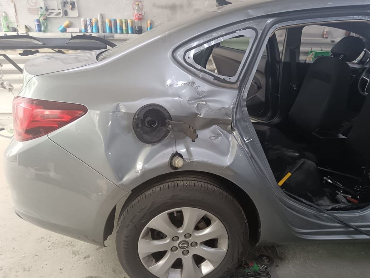 Opel Astra sedan gri cu aripa din spate lovită și ușa demontată, înainte de reparație