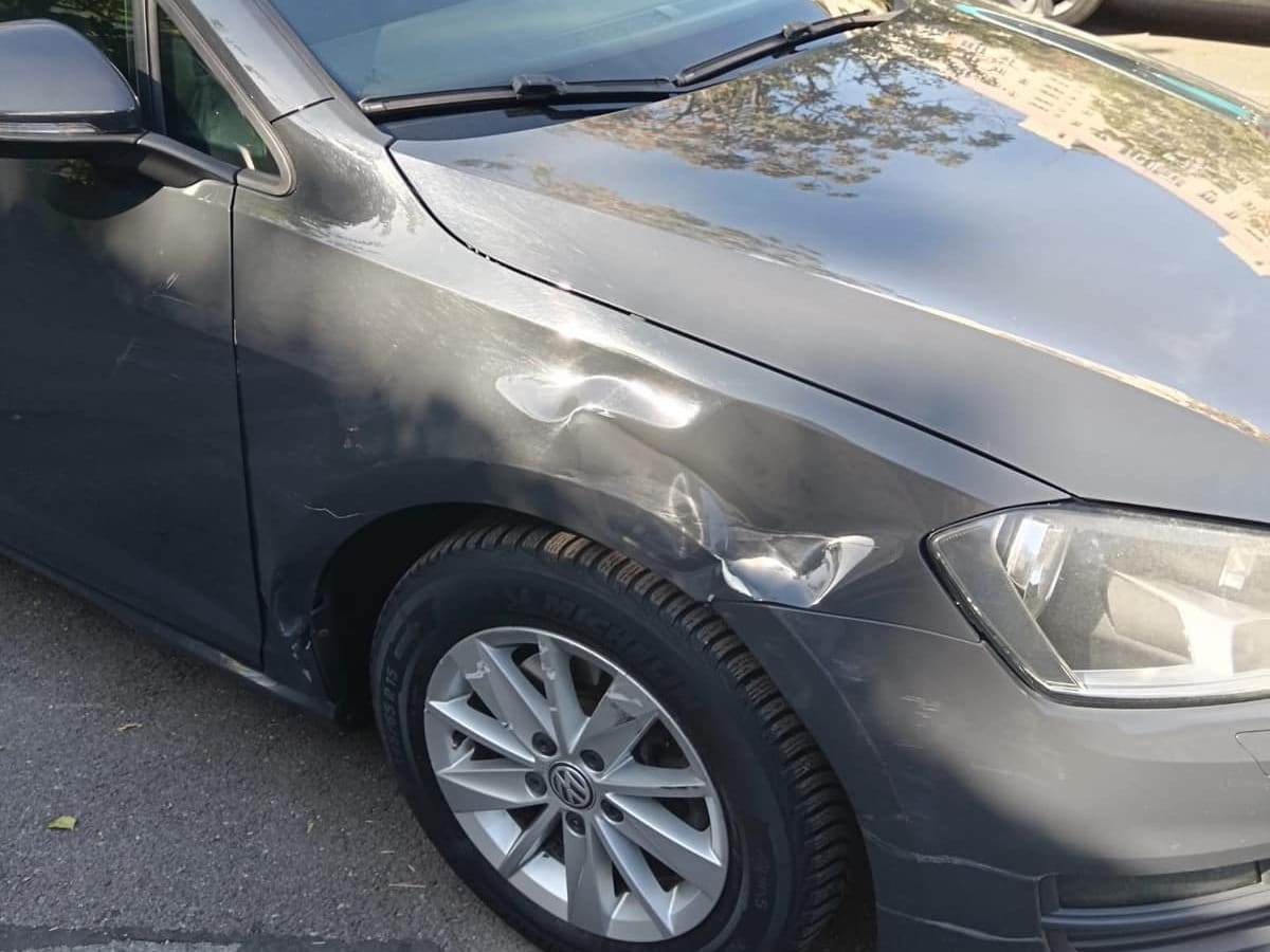 VW Golf gri cu aripa din față lovită deasupra roții, înainte de reparație