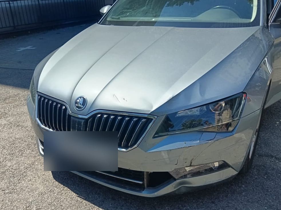 Skoda Superb gri cu bara din față crăpată și farul lovit, înainte de reparație