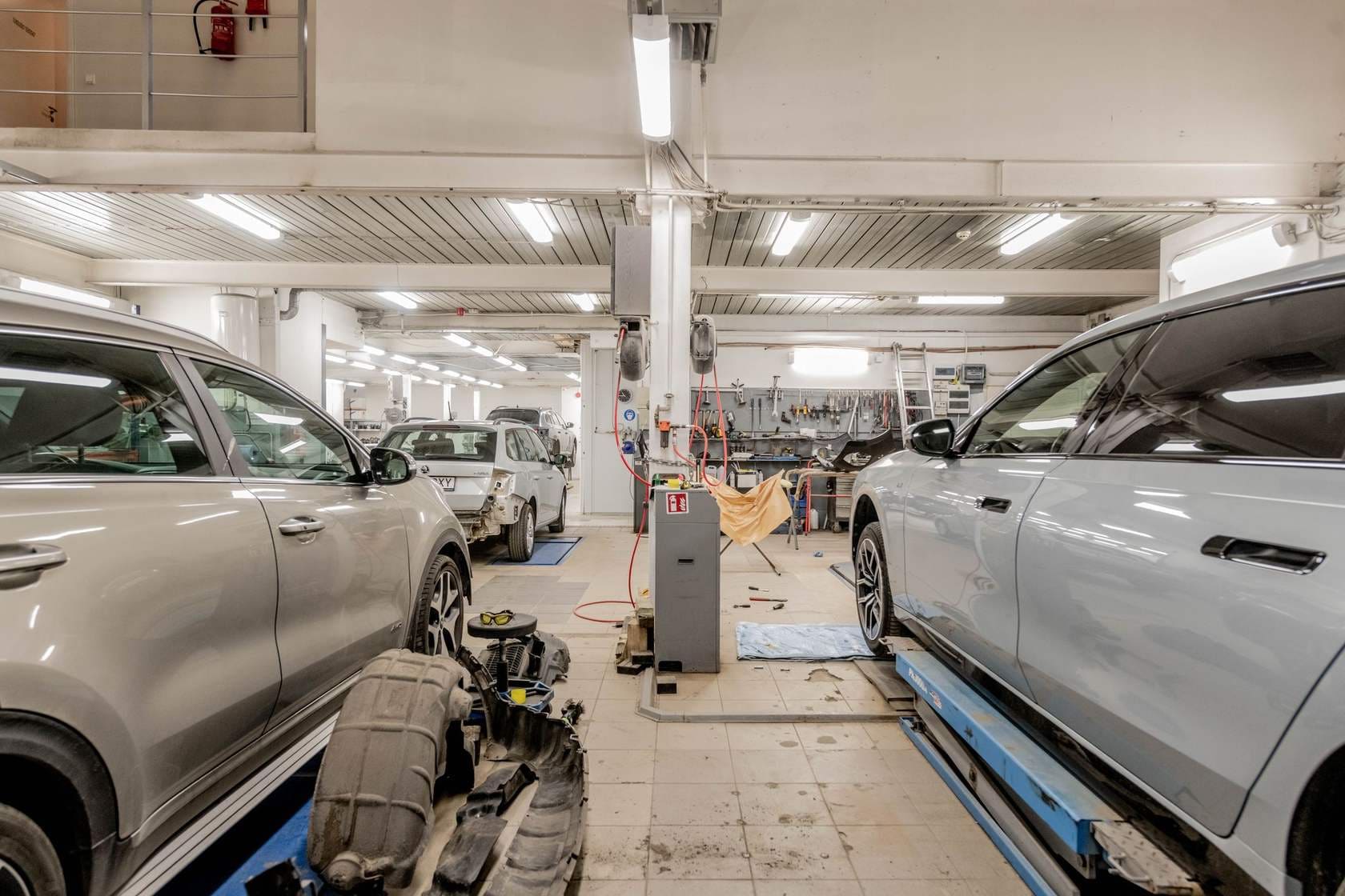 Atelier auto luminos, cu mașini în lucru pe elevatoare și standuri