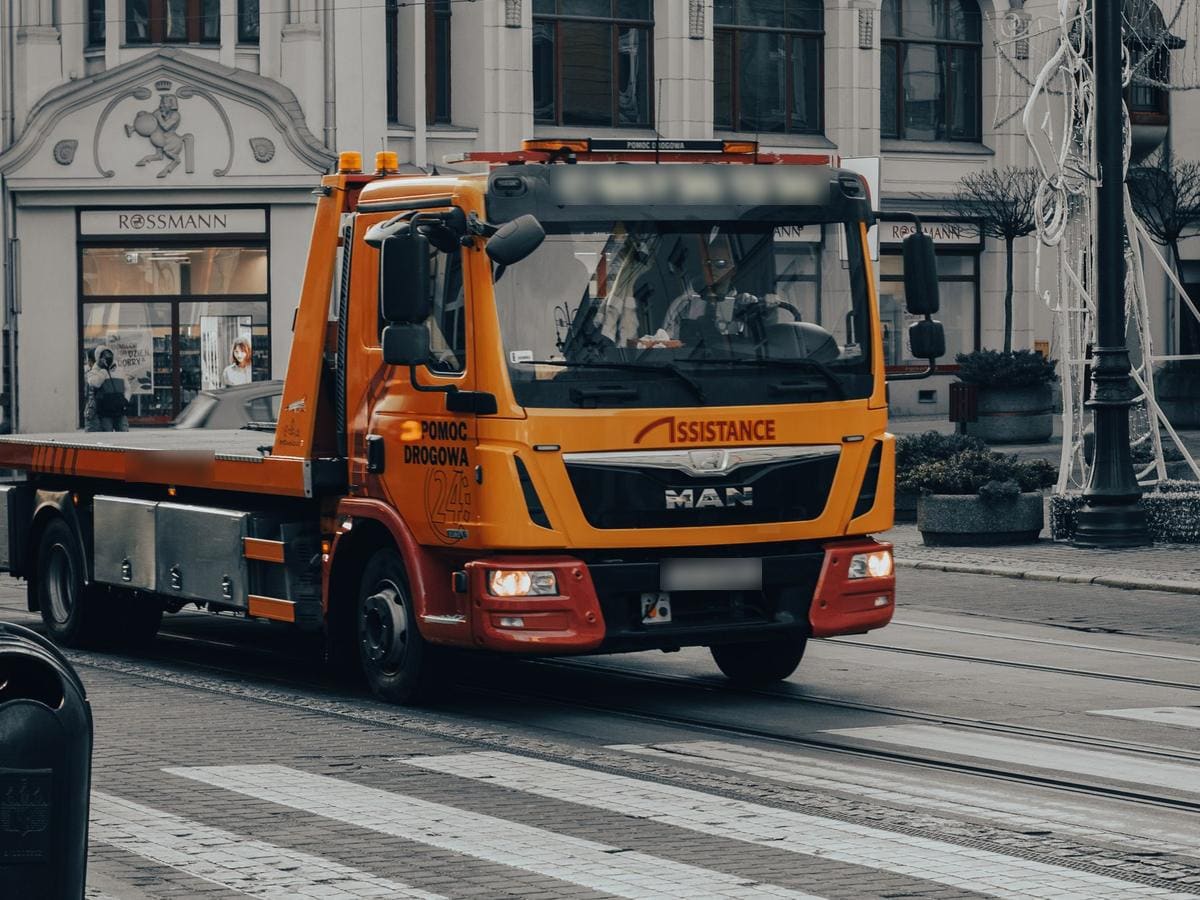 Camion cu platformă de tractare pe o stradă din oraș