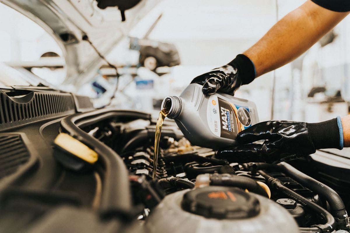 Mecanic care toarnă ulei de motor într-un motor deschis